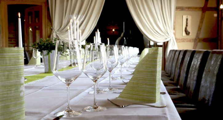 Festlich gedeckte lange Tafel mit Kerzen und Weingläsern in der Mühlenscheune